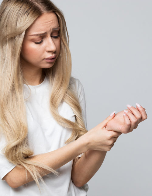 woman holding her painful wrist caused by prolonged work on the computer, laptop/Carpal tunnel syndrome, arthritis, neurological disease concept/Numbness of the hand/